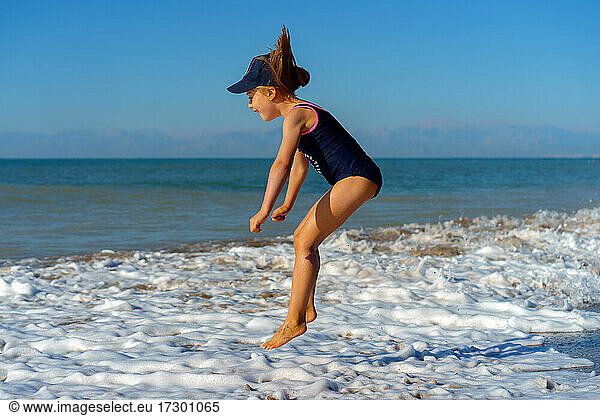 Junges Mädchen springt im Sommerurlaub glücklich ins Meer.