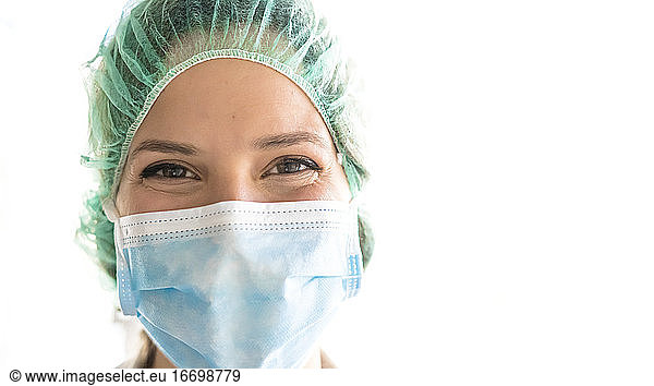 Junges medizinisches Fachpersonal lächelt mit Verfahrensmaske auf dem Gesicht