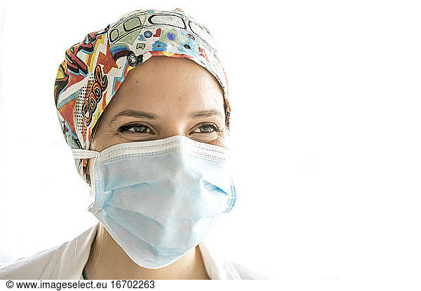 Junges medizinisches Fachpersonal lächelt mit Verfahrensmaske auf dem Gesicht