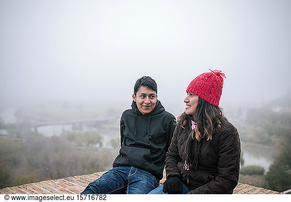 Junges mexikanisches Paar interagiert an einem nebligen Tag