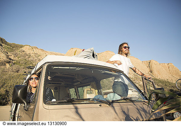 Junges Paar in Mini-Van genießt Urlaub bei strahlend blauem Himmel