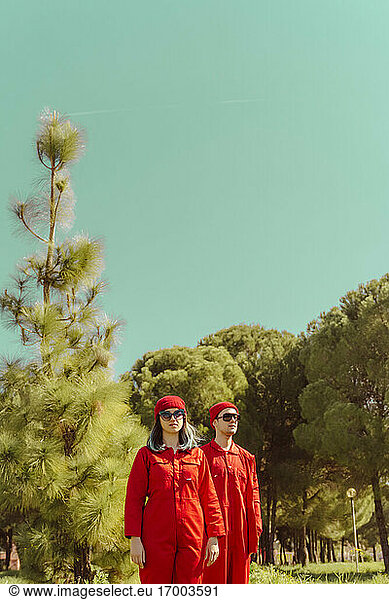 Junges Paar in roten Overalls und Hüten steht in der Natur