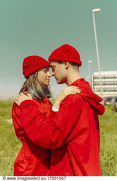 Junges Paar in roten Overalls und Hüten steht Kopf an Kopf und sieht sich an