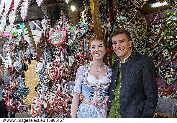 Junges Paar in traditioneller traditioneller traditioneller traditioneller traditioneller traditioneller traditioneller traditioneller Tracht vor Lebkuchenherzen  Lebkuchenstand  Wiesn  Wies'n  Oktoberfest  München  Oberbayern  Bayern  Deutschland  Europa