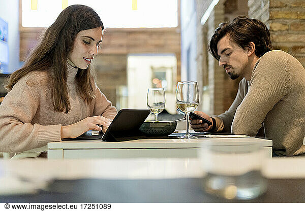 Junges Paar nutzt drahtlose Technologie am Restauranttisch