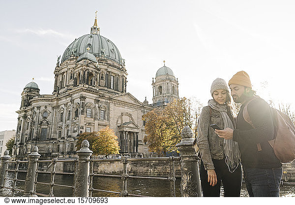 Junges Paar nutzt Smartphone mit dem Berliner Dom im Hintergrund  Berlin  Deutschland