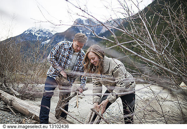 Junges Paar sammelt Holz für Lagerfeuer gegen Berge