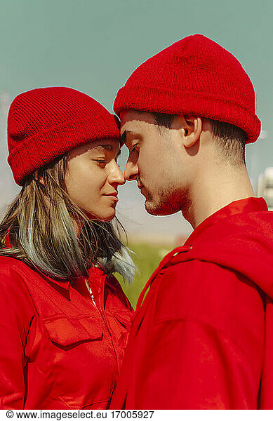 Junges  rot gekleidetes Paar steht Kopf an Kopf mit geschlossenen Augen