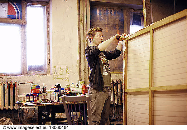 Künstler befestigt Leinwand auf Holzrahmen in einem Workshop