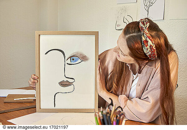 Künstlerin zeigt Zeichnung Kunst Bilderrahmen gegen Wand zu Hause