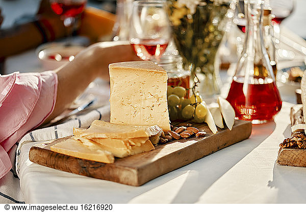 Käseteller und Wein auf einem Tisch mit Menschen im Hintergrund