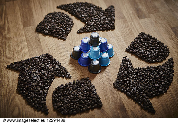 Kaffeebohnen  die ein Recycling-Symbol um Plastik-Kaffeepads bilden