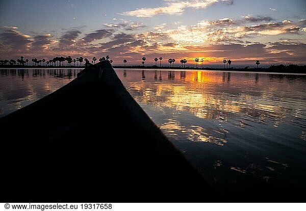 Kajakfahren auf dem Rio Negro bei Sonnenaufgang. Die Sonne geht hinter den Wolken auf und erzeugt schöne Spiegelungen auf dem Fluss im paraguayischen Pantanal