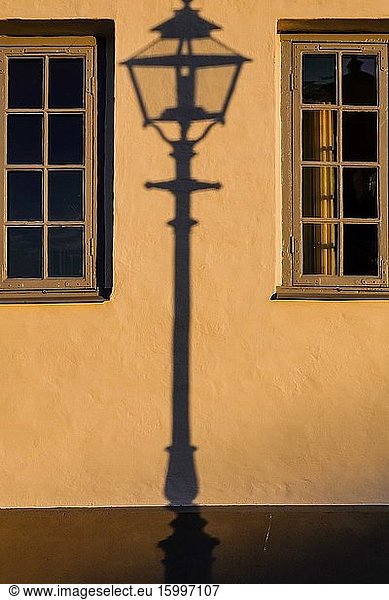 Kalmar  Sweden The shadow of an old lamppost on a yellow wall at sunset.