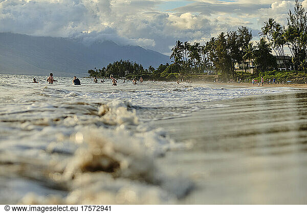 Kamaole beach tourists play in the waves right before sunset  Maui.