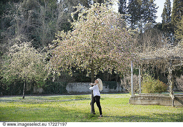 Kaukasische Frau umarmt Baumstamm im Frühling