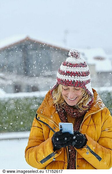 Kaukasische junge Frau genießt mit einem Mobiltelefon im Schnee im Freien im Winter Zeit. Navarra  Spanien  Europa.