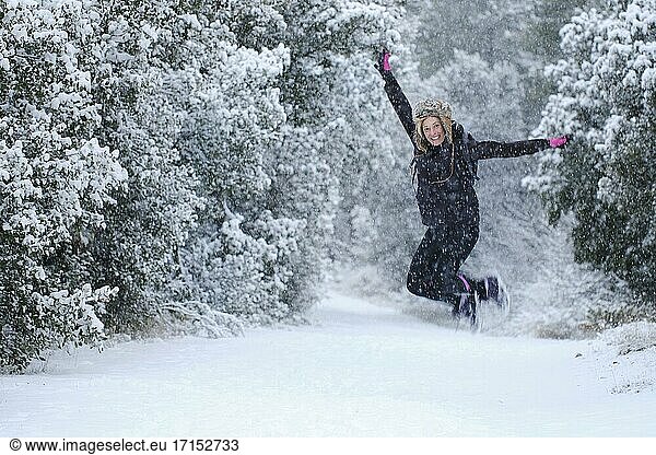 Kaukasische junge Frau genießt Springen im Schnee im Freien im Winter Zeit. Navarra  Spanien  Europa.