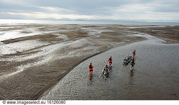 Kayakers pulling their kayak in a river in a river delta of Scoresbysund  Greenland