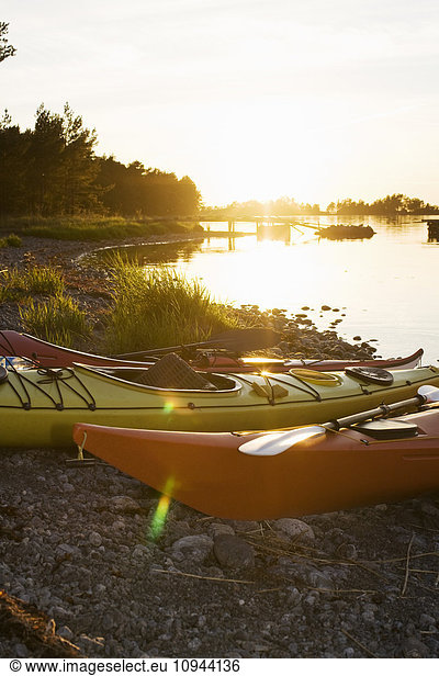 Kayaks moored on lakeshore during sunset