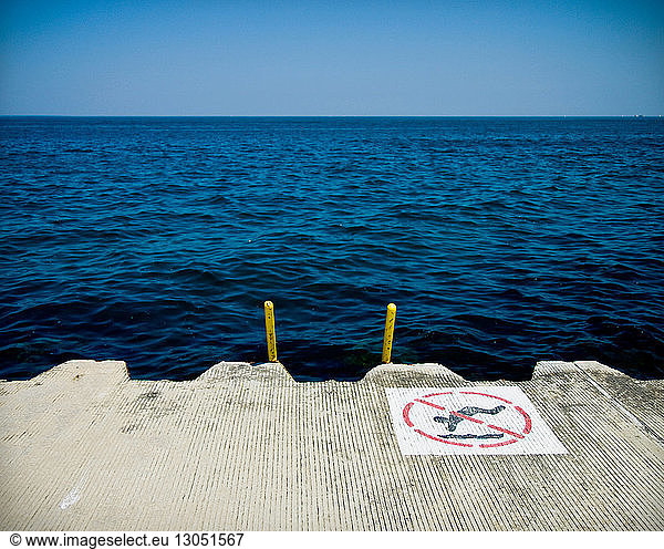 Kein schwimmendes Schild am Pier über dem Meer vor klarem blauen Himmel