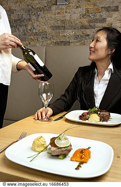Kellner präsentiert einer Geschäftsfrau in einem Luxusrestaurant Rotwein