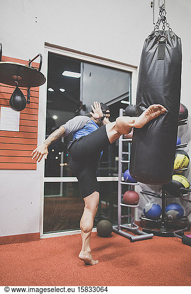kick boxer kicks punching bag in the gym.