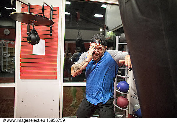 Kickboxer schützt sein Gesicht beim Training am Sandsack