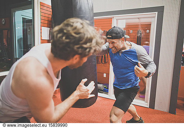 kickboxing instructor and client practice in the gym on punching bag.