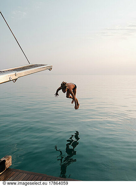 Kid diving from yacht into the sea.