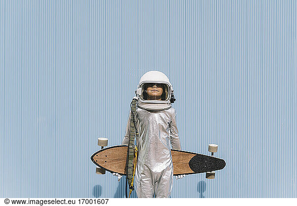 Kid dressed as an astronaut with longboard