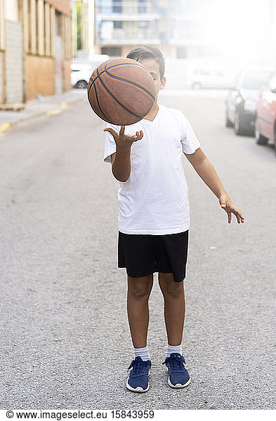 Kid playing basketball alone in a street court