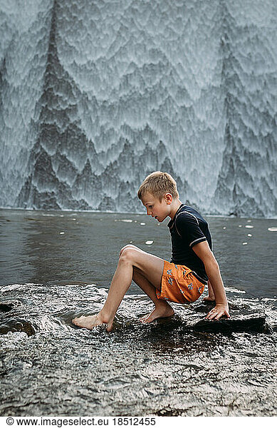 Kid playing in stream in front of waterfall