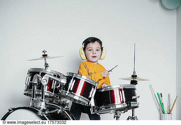 Kid wearing ear protective headphones while playing drums