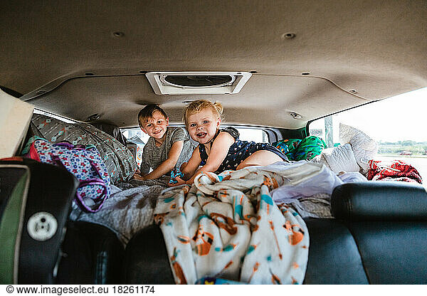 Kids in bed of truck camper ready for road trip