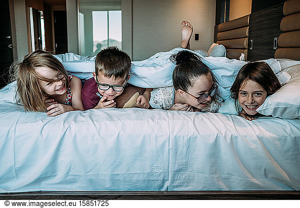 kids laying on bed in hotel room on vacation