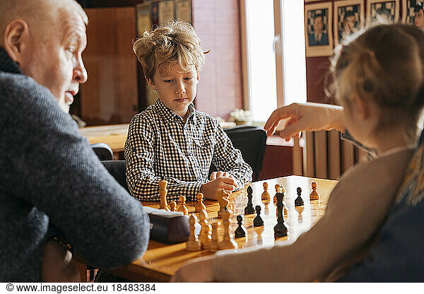 Kids playing chess with grandfather at country club