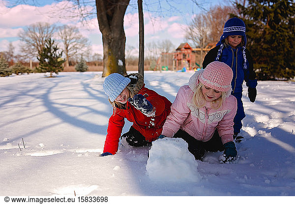 Kids playing outisde in winter making a snowball