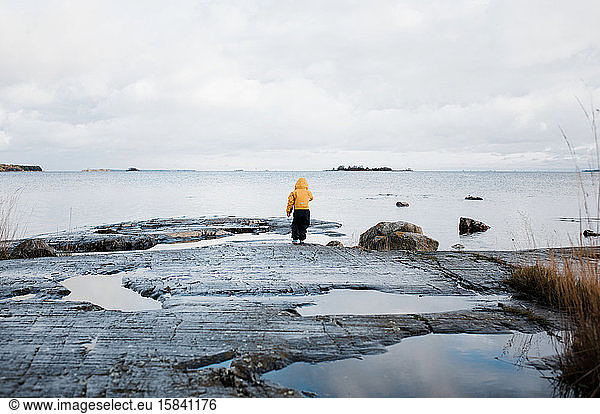 Kind auf Felsen stehend mit Blick aufs Meer in den schwedischen Schären