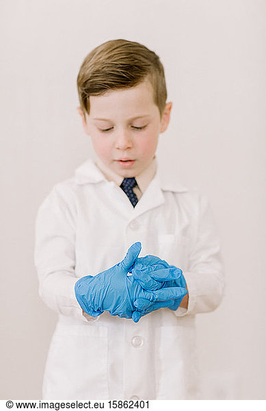 Kind im Laborkittel zieht Handschuhe an