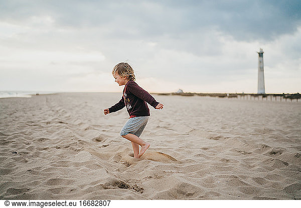 Kind Junge Kind spielt am Strand an einem bewölkten Tag