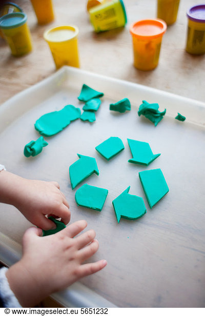 Kind macht Recycling-Symbol aus Spiel-Ton