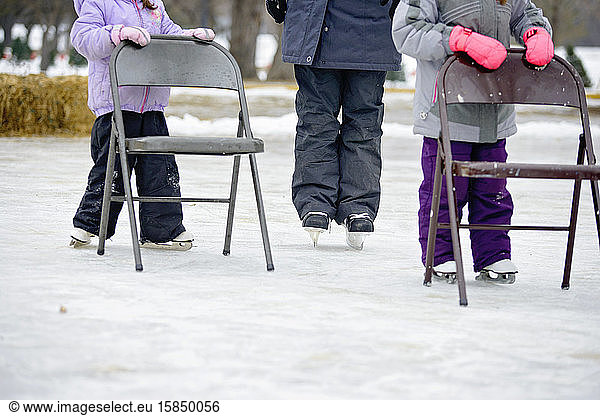 Kinder lernen Schlittschuhlaufen auf Stühlen