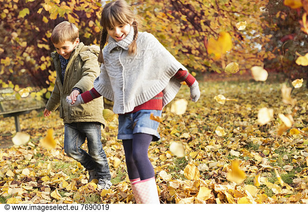 Kinder spielen im Herbstlaub