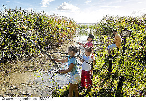 Kinder spielen mit Holzstöcken am Wasserlauf  Darß  Mecklenburg-Vorpommern  Deutschland