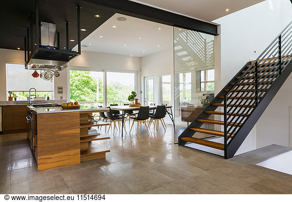 Kitchen  dining room and American walnut wood and black powder coated cold rolled steel stairs inside a modern cube style home  Quebec  Canada