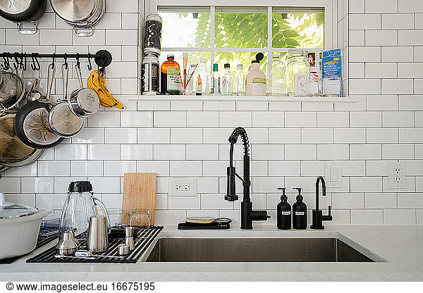 Kitchen sink with dishes on dry rack and hanging pans