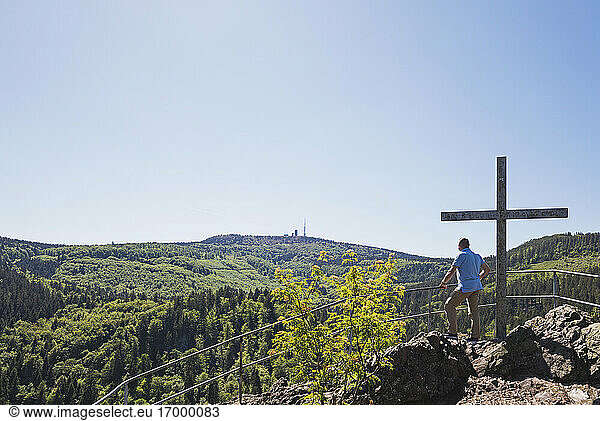 Klarer Himmel über einem älteren Wanderer  der den Thüringer Wald von einem Aussichtspunkt aus bewundert