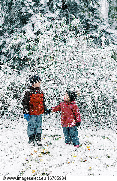 Kleine Kinder erleben einen Schneefall im Oktober in Neuengland