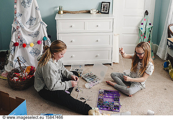 Kleine Mädchen kreieren Schmuck auf dem Boden des Schlafzimmers